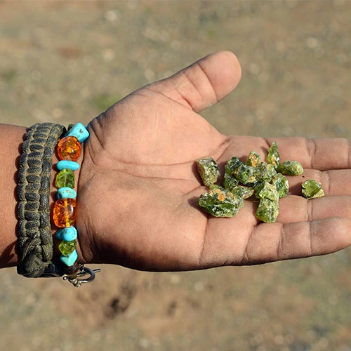 small peridot stones in someone's hand. From their bracelet, they appear to be a native American Indian