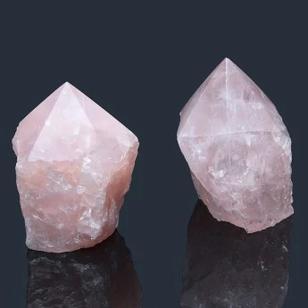 two rose quartz carvings with a flat base and terminated point